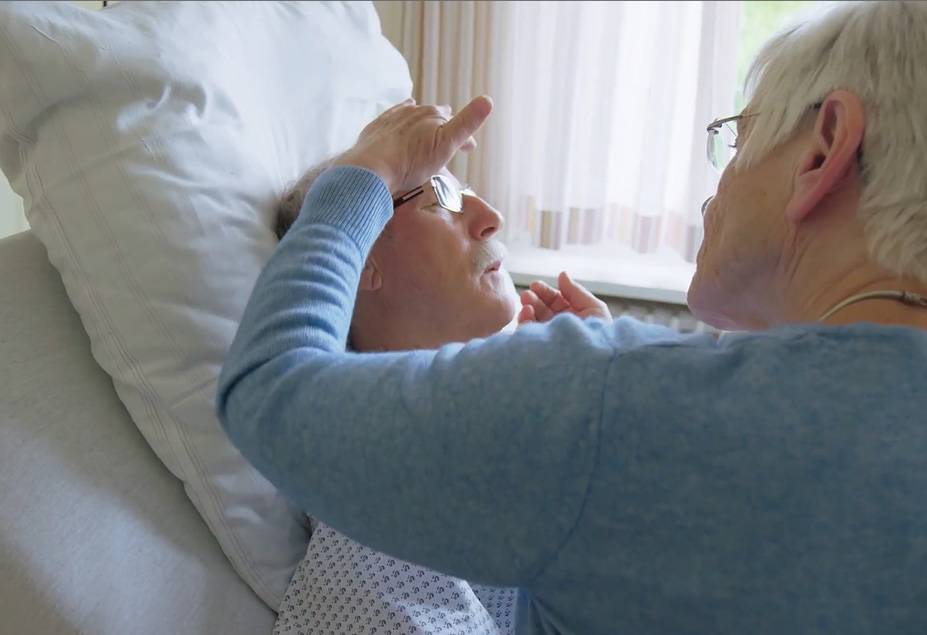 healthcare professional examines patient in hospice bed