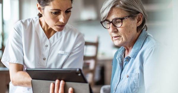 healthcare professional shows elderly person information on a mobile tablet