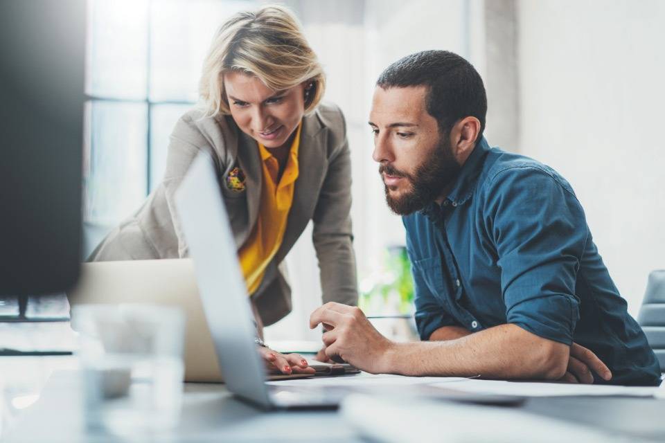 Two office professionals looking at a laptop, happy