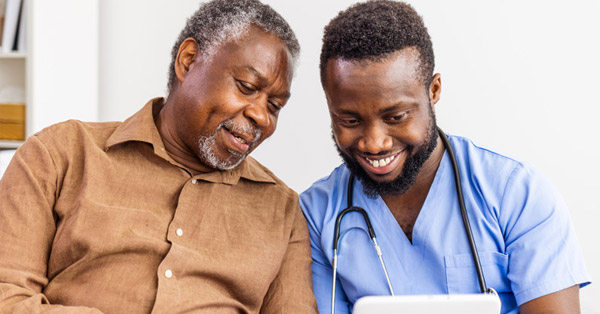 BIPOC healthcare professional shows BIPOC elderly client information on a tablet