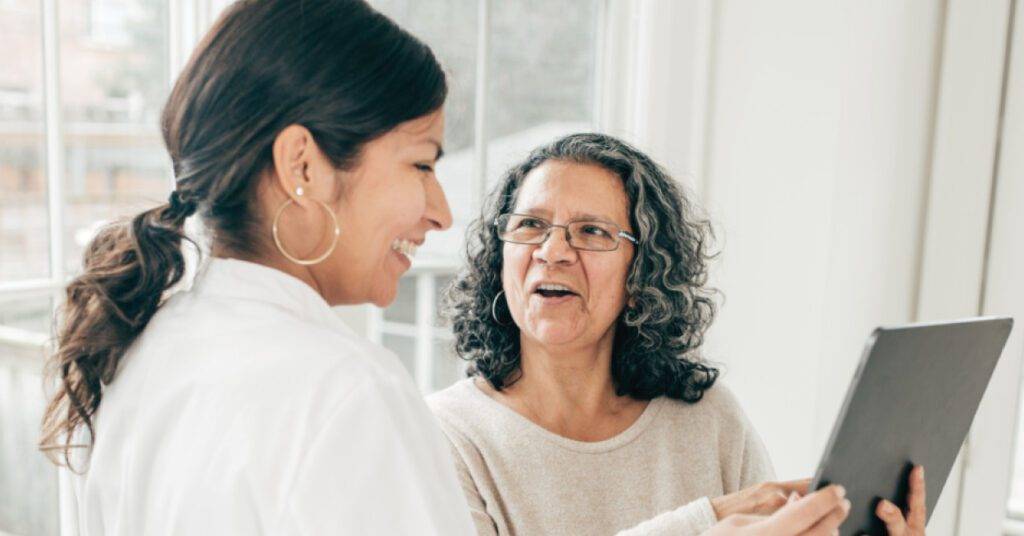 younger woman shows elderly woman something on a mobile tablet