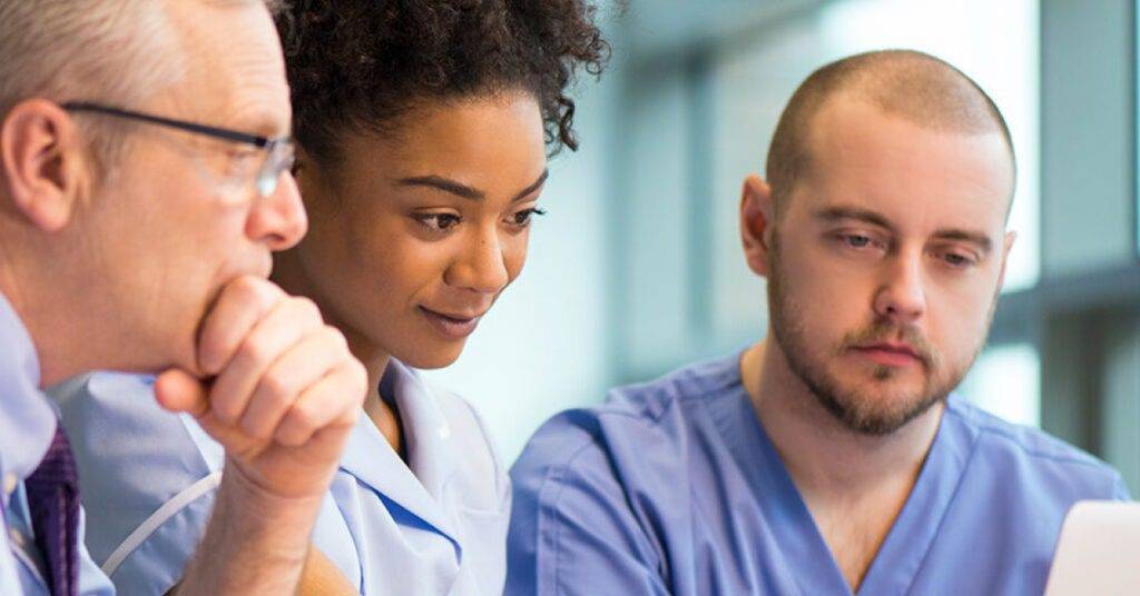 three healthcare professionals look at computer screen together