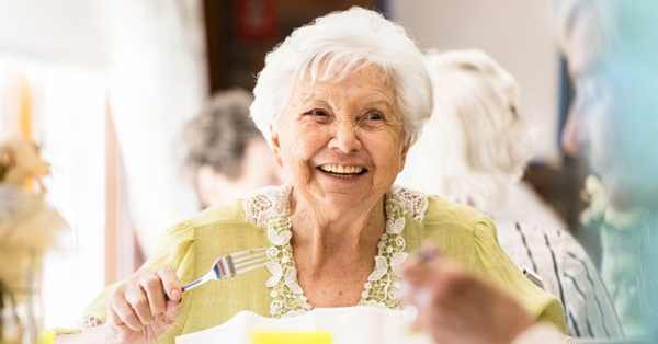 Elderly woman enjoys a meal while holding a fork