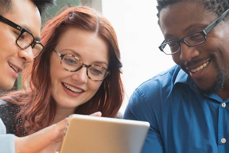 Three professionals look at mobile tablet; diveristy at work