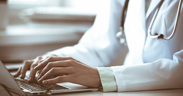 hands of healthcare professional typing on laptop