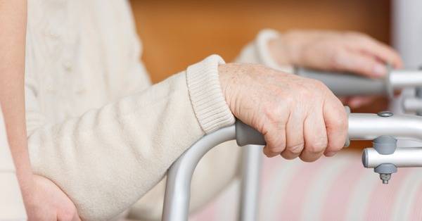 hands of elderly person gripping walker