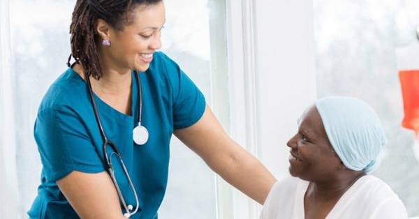 BIPOC healthcare professional assists BIPOC infusion patient with a smile