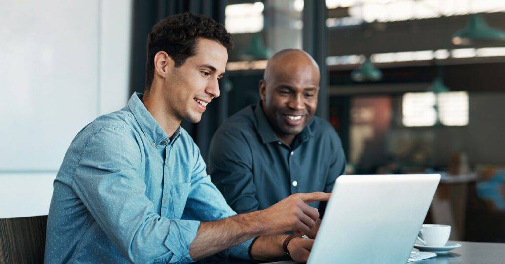 two professionals look at laptop together