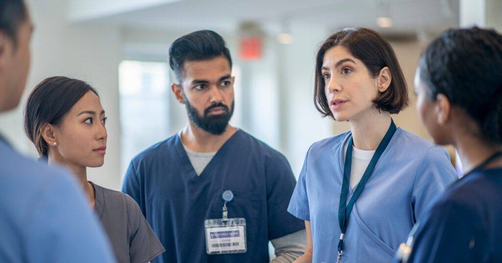 diverse staff of healthcare professionals talk in a circle