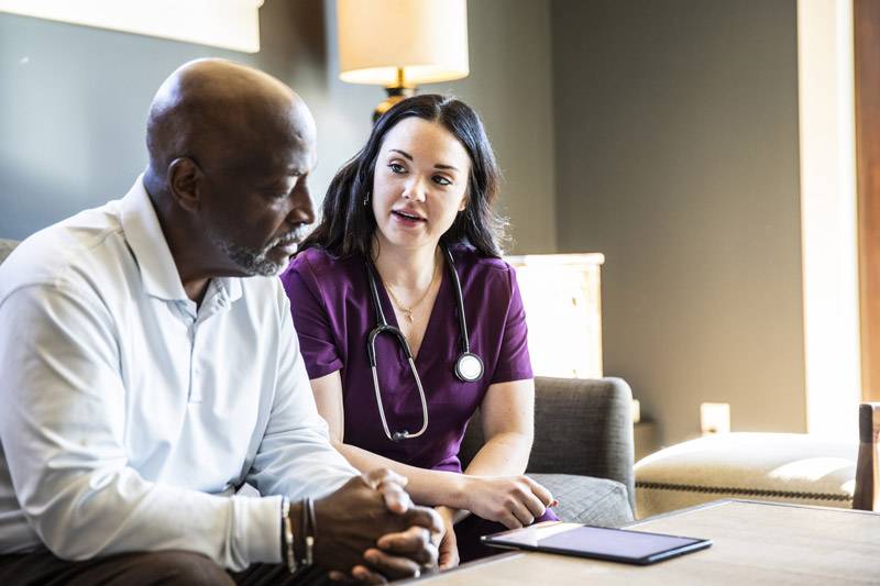 care giver and medial professional discussing AI created plan shown on mobile device.