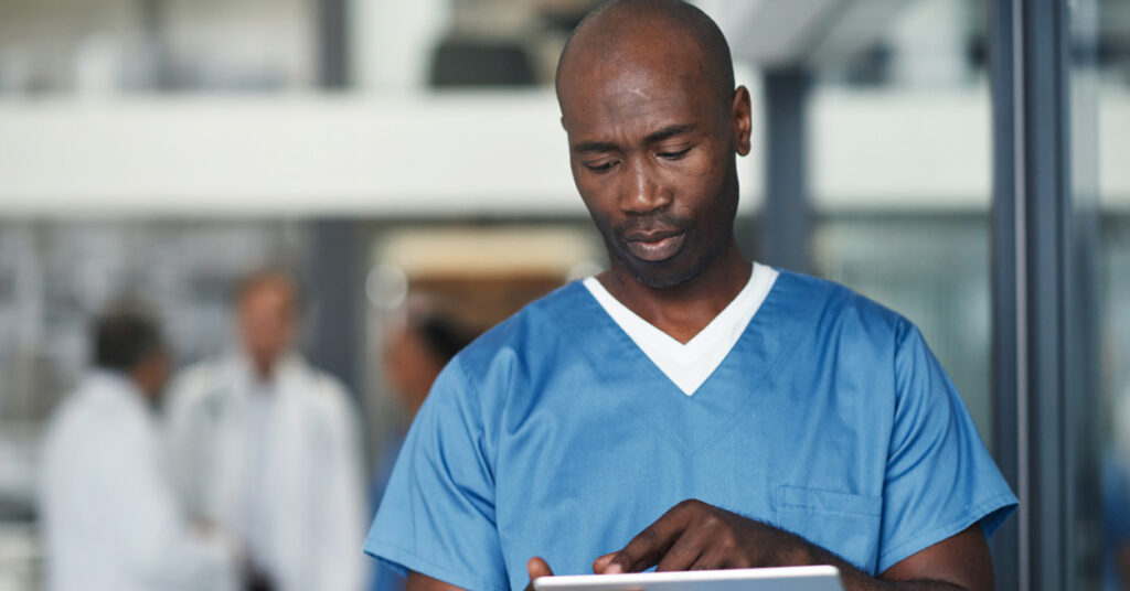 BIPOC healthcare professional looks at mobile tablet