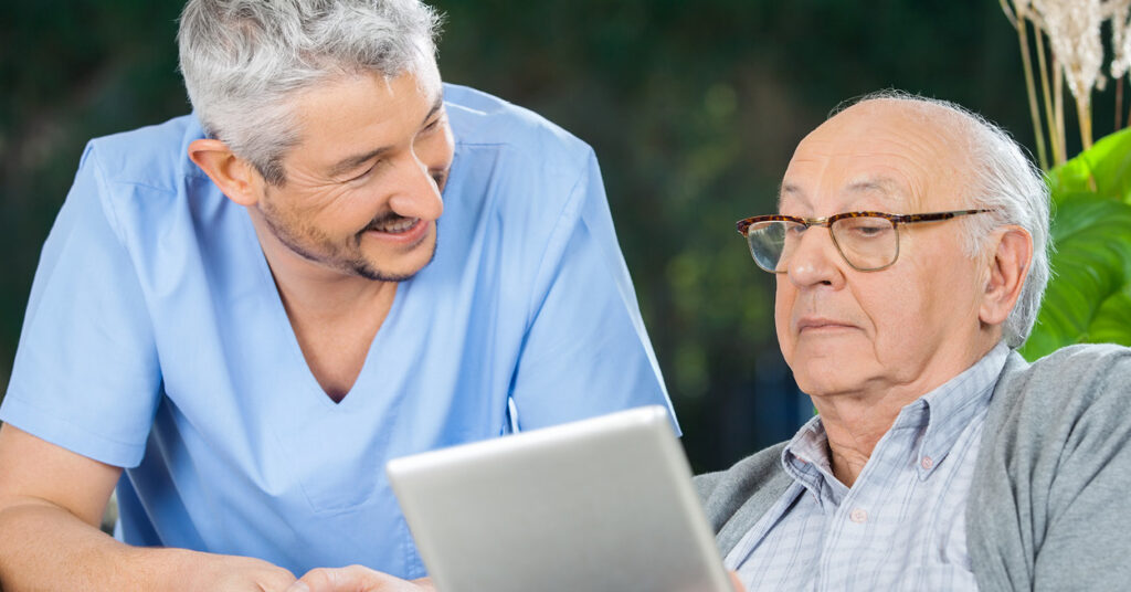 healthcare professional talks to elderly man using mobile tablet