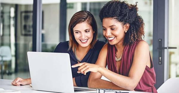 Two ladies reviewing content on a laptop