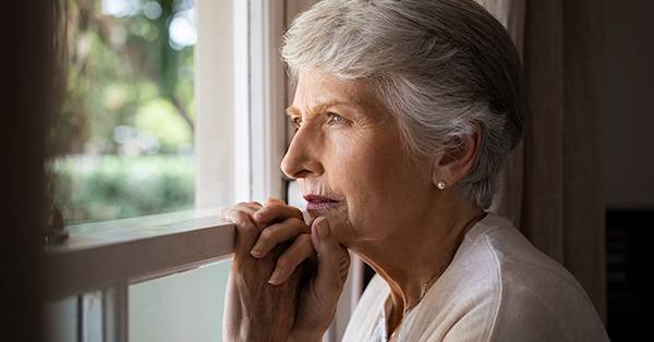elderly woman looks out the window