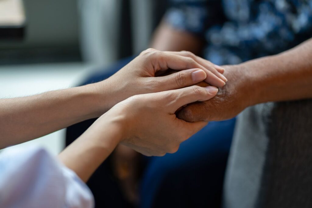 Close-up of a caregiver gently holding an older resident’s hand