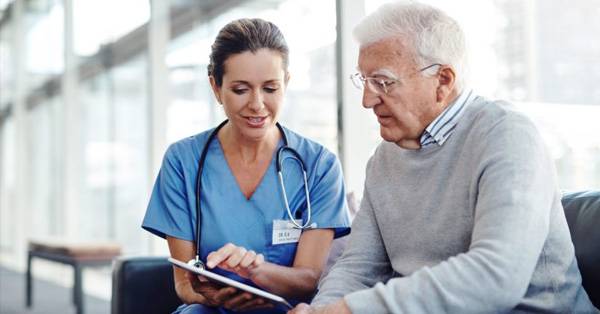 Medical professional and patient on couch talking with tablet device